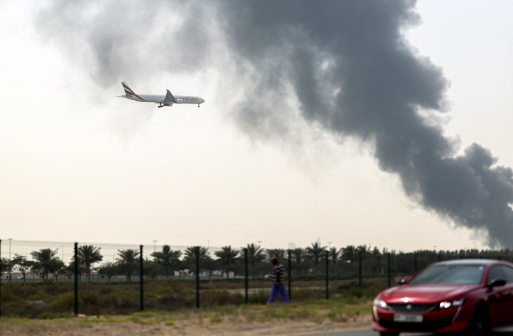 Risky landing: An Emirates Boeing 777 aircraft prepares for landing on Monday as a smoke plume rises from an ongoing fire near Dubai International Airport in Dubai. Flights were gradually resuming at Dubai airport on Monday, March 16, 2026,  previously the world&rsquo;s busiest for international flights, the airport operator said.