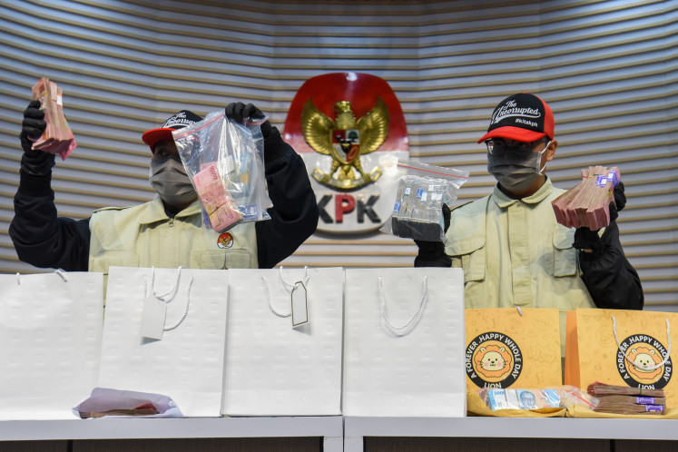 Corruption Eradication Commission (KPK) investigators hold up cash seized in the arrest of Cilacap Regent Syamsul Auliya Rachman, at a press briefing on March 14 at the antigraft body headquarters in Jakarta.