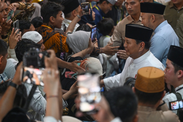President Prabowo Subianto (second right, in white shirt) and his son, fashion designer Didit Hediprasetyo (right, in light blue shirt), greet a crowd of well-wishers March 21, 2026, at an Idul Fitri gathering at the Presidential Palace complex in Central Jakarta.