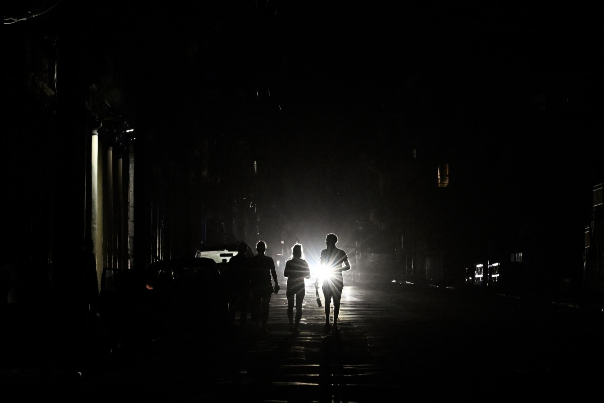 People walk on a street without electricity during a nationwide blackout in Havana on March 21, 2026. A power outage struck the entire island of Cuba on March 21, 2026, the energy ministry said, in the second nationwide blackout in less than a week as its grid struggles under a US oil blockade.