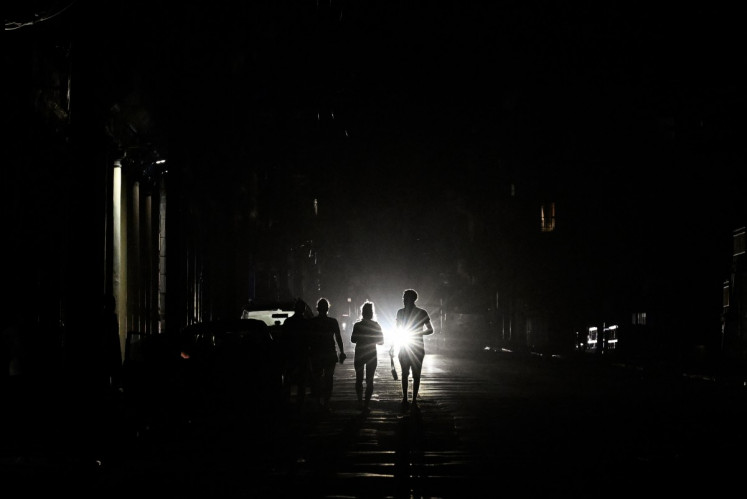 People walk on a street without electricity during a nationwide blackout in Havana on March 21, 2026. A power outage struck the entire island of Cuba on March 21, 2026, the energy ministry said, in the second nationwide blackout in less than a week as its grid struggles under a US oil blockade.