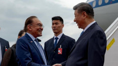 Malaysian Prime Minister Anwar Ibrahim (left) greets Chinese President Xi Jinping (right) as the latter arrives in Kuala Lumpur on April 15, 2025 for a three-day visit to the Southeast Asian country.