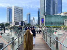 Visitors prepare to take selfies at the TransJakarta bus stop pavilion at the Hotel Indonesia traffic circle amid light traffic during the Eid al-Fitr homecoming and holiday period in Jakarta on Monday, March 23, 2026.