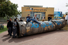 Children play with a graffitied missile casing on March 23, 2026, a day after it landed in the playground of an elementary school in the Israeli settlement of Peduel in the occupied West Bank amid the United States-Israeli war on Iran.