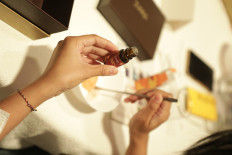 A person prepares a skincare treatment using a Juara Beauty product.

