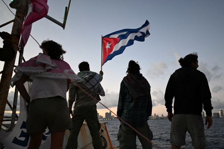 Brazilian activist Thiago Avila waves a Cuban flag on board the vessel Maguro -- symbolically renamed &ldquo;Granma 2.0&ldquo; as a tribute to the yacht used by Fidel Castro's guerrilla fighters to launch their revolution in 1956 -- as it arrives from Mexico with humanitarian aid as part of the Nuestra America convoy, docking at the port of Havana on March 24, 2026. 