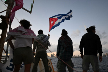 Brazilian activist Thiago Avila waves a Cuban flag on board the vessel Maguro -- symbolically renamed &ldquo;Granma 2.0&ldquo; as a tribute to the yacht used by Fidel Castro's guerrilla fighters to launch their revolution in 1956 -- as it arrives from Mexico with humanitarian aid as part of the Nuestra America convoy, docking at the port of Havana on March 24, 2026. 