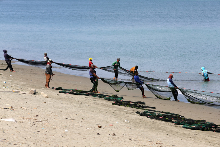 Traditional fishermen pull a beach seine net while fishing on March 26 along the coast of Kutaraja in Banda Aceh.