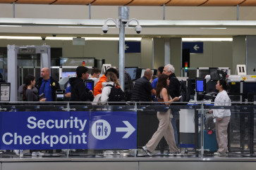 TSA agents screen passengers as travelers wait for passenger screening at a Transportation Security Administration (TSA) checkpoint inside the Tom Bradley International Terminal (TBIT) at Los Angeles International Airport (LAX) in Los Angeles, California on March 23, 2026.