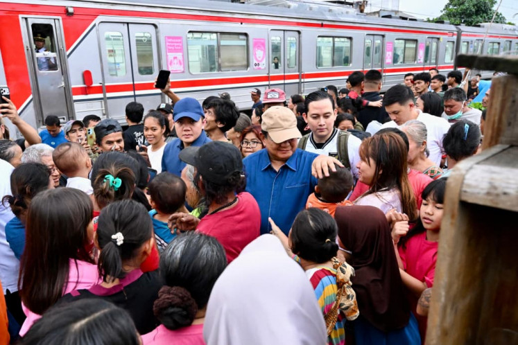 President Prabowo Subianto (center) greets a child on Thursday during his impromptu visit to an impoverished community in Senen, Central Jakarta. The President, accompanied by Cabinet Secretary Teddy Indra Wijaya (left) and a small security detail, reportedly promised to build proper housing and sanitary facilities for residents in the area.