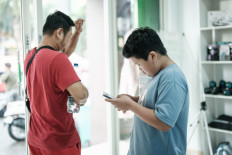 Bradley Rowen Liu, an 11-year-old boy learning Python, a programming language, watches a video on social media on his smartphone as he leaves the coding academy with his father Handri Liu in Jakarta on March 25, 2026. 