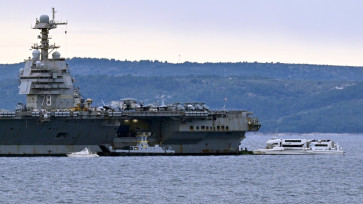 Harbour tugboats and other civilian vessels approach the US Navy aircraft carrier USS Gerald R. Ford at an anchor point off the Croatian coastal city of Split on March 28, 2026, for a scheduled port visit and maintenance stop following involvement Middle East war operations. 