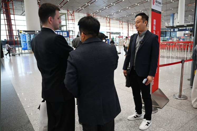 Zhao Bin, a Chinese business traveler (right), speaks to media after checking in for a flight to Pyongyang, North Korea, at Beijing airport on March 30, 2026. Air China restarted direct flights between Beijing and Pyongyang on March 30 after a six-year hiatus, another sign isolated North Korea is gradually opening up following the resumption of train services between the capitals.