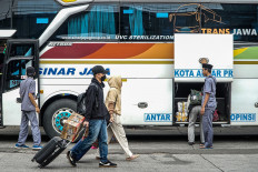 Passengers disembark on March 24, 2026, from an intercity coach at the Kampung Rambutan bus terminal in East Jakarta, amid the post-Idul Fitri 'balik' (return) travel surge after the Islamic holiday.