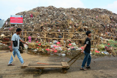 Workers walk past piles of garbage on Wednesday at Kramat Jati market in East Jakarta.