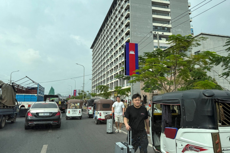 Workers walk with their luggage out from a suspected scam center compound in Sihanoukville on January 15, 2026.