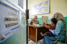 Protect young lives: A doctor (left) attends to a toddler receiving a measles vaccine on March 27, 2026, at the Ibrahim Adjie community health center (Puskesmas) in Bandung, West Java. 
