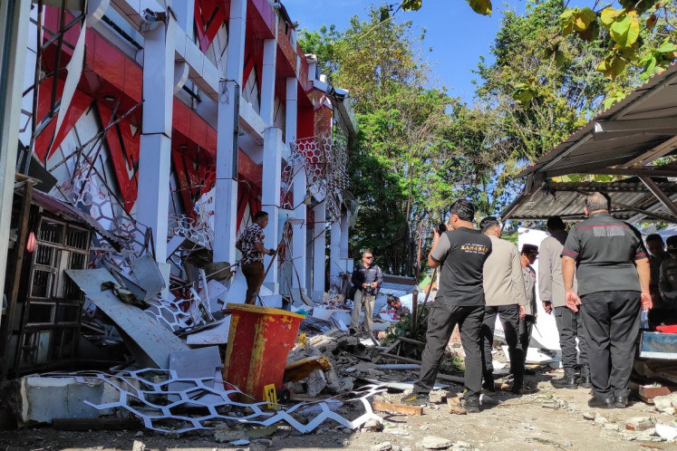 Police officers look at a building of the North Sulawesi's National Sports Committee of Indonesia (KONI) damaged following a severe 7.4-magnitude offshore quake in Manado, North Sulawesi on April 2, 2026. 