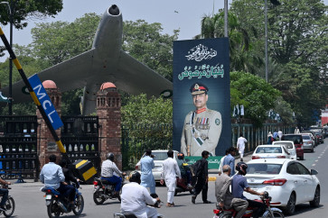 Commuters ride past a poster featuring Pakistani Army Chief General Syed Asim Munir, along a road in Lahore on May 16, 2025. 