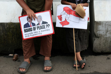 Boys in solidarity with Palestinians hold signs as they take part in a protest, outside the US embassy, against Israel and demanding that the Indonesian government cancel the proposed multinational peacekeeping force for Gaza, following President Prabowo Subianto invitation to Washington later this month for the first meeting of US President Donald Trump's Board of Peace, in Jakarta, February 13, 2026.