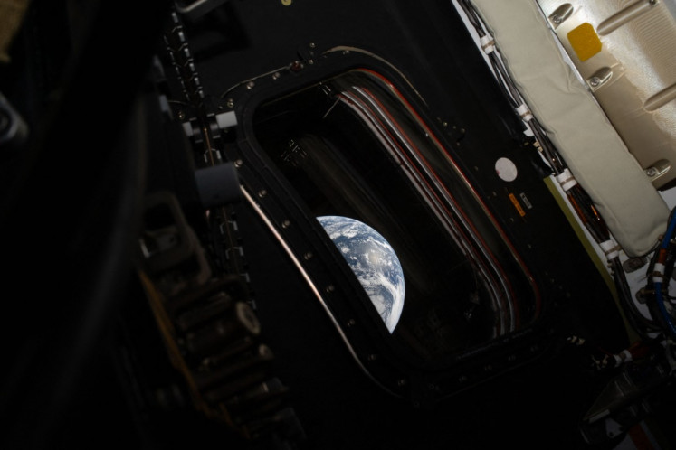 This handout picture provided by NASA shows a view of Earth taken by NASA astronaut and Artemis II commander Reid Wiseman from one of the Orion spacecraft's four main windows after completing the translunar injection burn on April 2, 2026. Four astronauts blasted off aboard a massive NASA rocket April 1 on a long-anticipated journey around the Moon, the first crewed lunar flyby in more than 50 years.