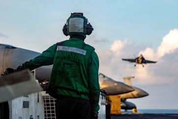 A United States Sailor observes flight operations as an F/A-18E Super Hornet, attached to Strike Fighter Squadron 14, prepares to make an arrested landing on the flight deck of Nimitz-class aircraft carrier USS Abraham Lincoln supporting Operation Epic Fury during the Iran war at an undisclosed location on March 26, 2026.