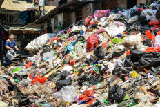 A woman throw away a bag of trash on April 2 at a temporary waste disposal site (TPS) at the Angke Tambora low-cost rental apartment complex in West Jakarta.