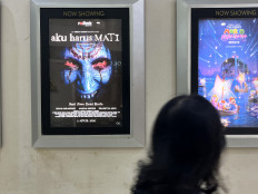 A woman walks past a promotional poster for the horror film &ldquo;Aku Harus Mati&rdquo; on April 6 at a Cinema XXI theater in a shopping mall in East Jakarta.