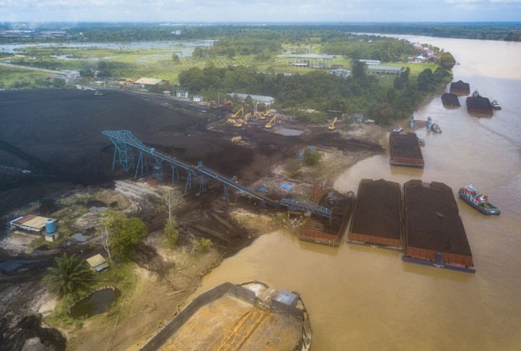 Coal storage barges float in a yard on May 6, 2024, next to the Batanghari River in Muaro Jambi, Jambi. 