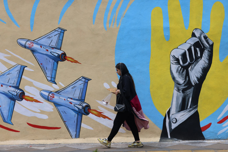 A woman walks past an anti-United States and anti-Israel mural on April 8 in Tehran.