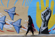 A woman walks past an anti-United States and anti-Israel mural on April 8 in Tehran.