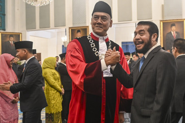 Constitutional Court Justice Liliek Prisbawono Adi (center) poses with former justice Anwar Usman (right) after the former's inauguration ceremony at the State Palace in Jakarta. Liliek replace former justice Anwar Usman who, retired after serving 15 years on the Constitutional Court.