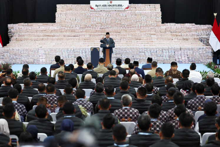 President Prabowo Subianto gestures on Friday while delivering a speech in front of stacks of rupiah banknotes representing fines paid by companies found to have operated illegally in forest areas during a ceremony at the Attorney General's Office (AGO) building in Jakarta. During the ceremony, the President also expressed his appreciation the work of the Forest Enforcement Task Force (Satgas PKH) in reclaiming forest areas that are used by plantation and mining companies.