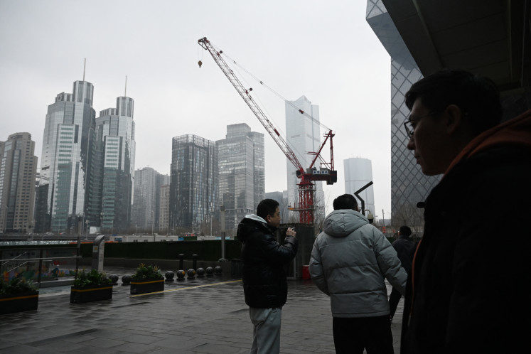 People chat outside office buildings in the central business district in Beijing on March 4, 2026.