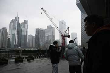 People chat outside office buildings in the central business district in Beijing on March 4, 2026.