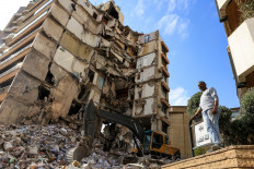 A man stands near a damaged building at the site of an Israeli strike carried out on April 9, 2026 in Tallet El Khayat in Beirut, Lebanon.