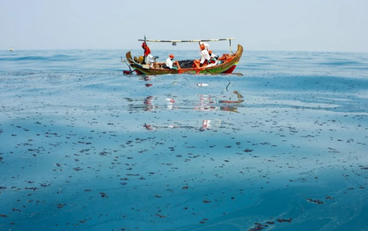 Local environmental officers clean up an oil spill on Aug. 12, 2019, in the Java Sea off Karawang regency, West Java.