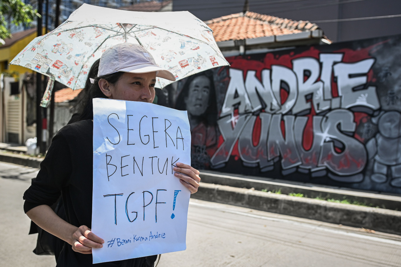 A woman carries a poster on April 12 calling for the creation of a joint fact-finding team (TGPF), during a commemoration marking 30 days since the acid attack on human rights activist Andrie Yunus, on Jl. Salemba I, Senen, Central Jakarta.