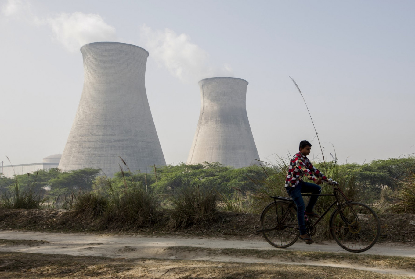 An Indian man cycles on March 27, 2018, along a dirt road next to the Norora Atomic Power Station near Norora in Uttar Pradesh state.
