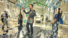 Waste lessons: At a house-like installation made of wire mesh and plastic bottles suspended on threads, Noud Sleumer explains the importance of separating waste at home during the exhibition on Feb. 5, 2026, where it can have the greatest impact across the system.