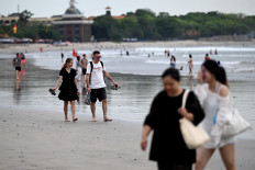 Beachgoers walk the sandy shores of Kuta, just south of Bali&rsquo;s provincial capital Denpasar, on April 8, 2026.