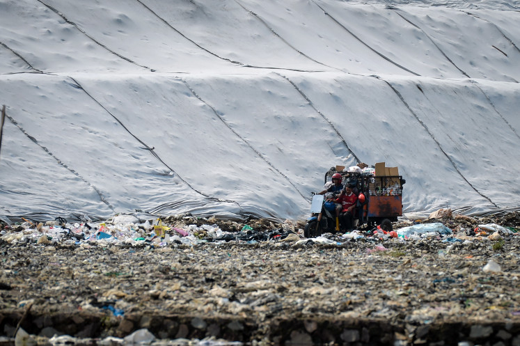 Endless waste crisis: A worker rides a garbage transport motorbike on April 14 at the Jatiwaringin landfill in Tangerang regency, Banten. The Environment Ministry has urged regional governments to immediately address open dumping practices at landfills and transition to a controlled landfill system, in which waste is covered with layers of soil periodically, with a deadline set for July 2026 to minimize environmental pollution and disaster risks.