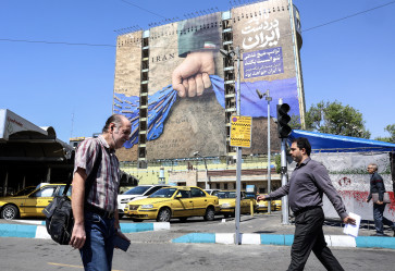 Stay united: Iranians walk past a large billboard on Wednesday, April 15, 2026, referring to the Strait of Hormuz in Tehran&rsquo;s Vanak Square. United States President Donald Trump said on Tuesday that US-Iran peace talks could resume this week, while Israel and Lebanon agreed to launch direct negotiations, signaling movement on two key fronts in efforts to ease the Middle East conflict.