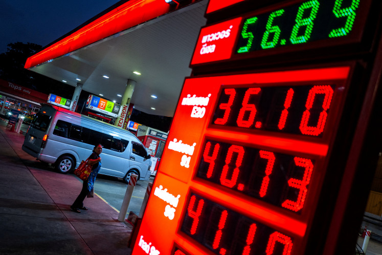 A woman looks at a fuel price board in front of a gas station amid the US-Israeli war on Iran, in Bangkok, March 26, 2026.