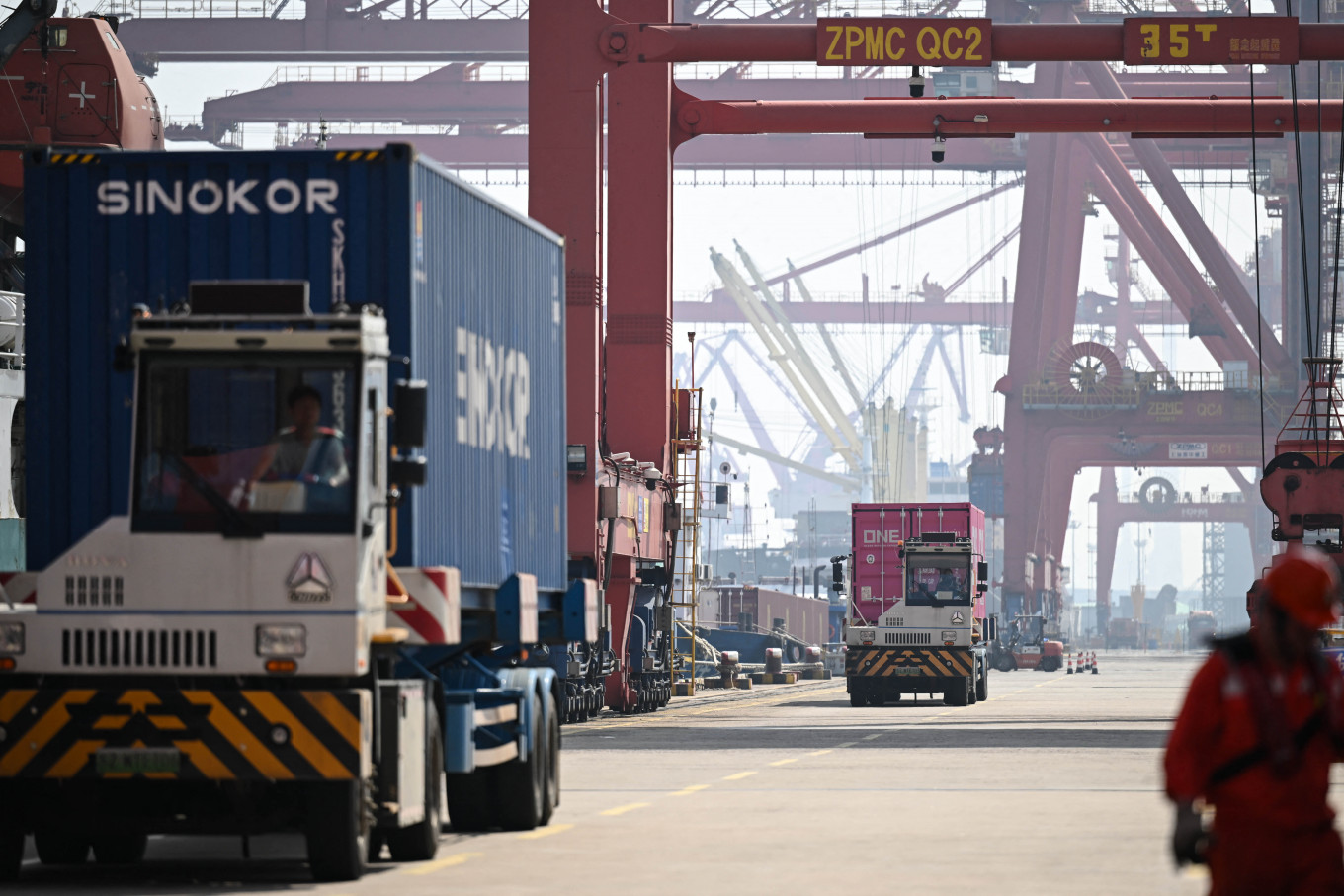 Trucks loaded with containers drive through a port in Zhangjiagang, in China's eastern Jiangsu province on April 15, 2026.
