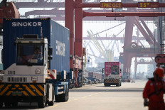 Trucks loaded with containers drive through a port in Zhangjiagang, in China's eastern Jiangsu province on April 15, 2026.