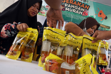 Residents purchase Minyakita cooking oil during a low-cost food program in Cisalak, Depok, West Java, Indonesia, Tuesday, April 7, 2026. The Depok city government, in cooperation with Bulog, organized the event, offering various staple foods below market prices to help stabilize supply and prices and ease the burden on residents.