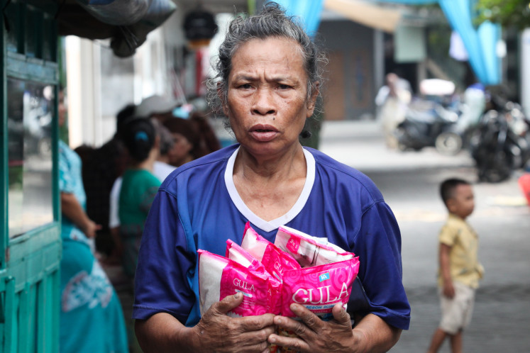 An elderly woman carries subsidized packaged sugar purchased at a low-cost market on Jl. Hang Tuah in Surabaya, East Java, on March 31. The sugar industry has warned of rising costs and land scarcity under a new refinery policy.
