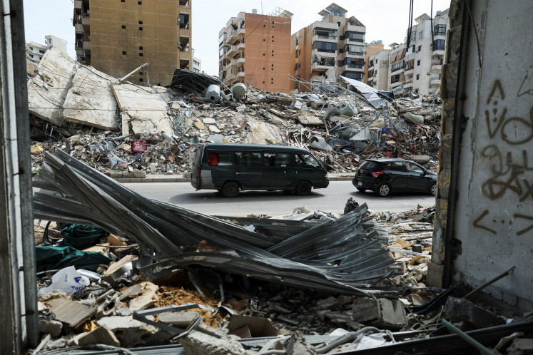 Vehicles drive past damaged buildings as displaced people return to their home on April 17 after a 10-day ceasefire between Lebanon and Israel went into effect, in the southern suburbs of Beirut.
