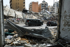 Vehicles drive past damaged buildings as displaced people return to their home on April 17 after a 10-day ceasefire between Lebanon and Israel went into effect, in the southern suburbs of Beirut.